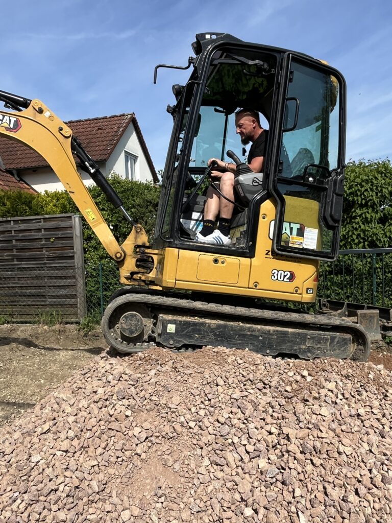 Zeigt einen Bagger der die Arbeit vorbereitet für Pflasterarbeiten